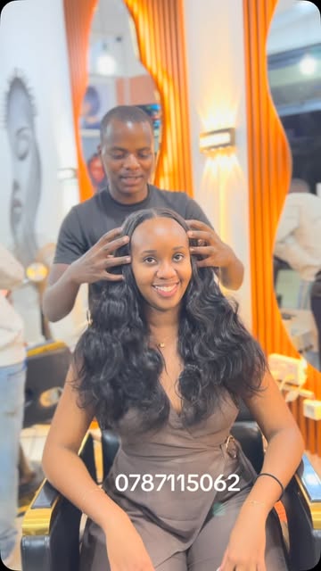 Smiling client with long centre-parted waves, stylist behind her in the salon